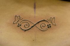 a woman's back with an artistic tattoo design on her left side ribcage