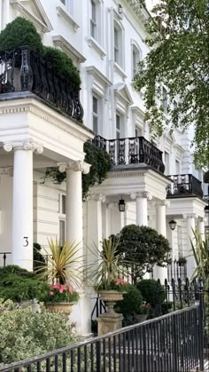 a row of white houses with balconies and plants growing on the balconys