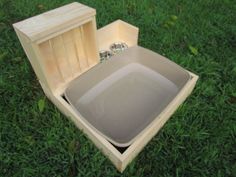 an empty wooden box sitting on top of green grass next to two silver rings in it