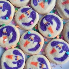 purple and white decorated sugar cookies with sprinkles on the top one has a smiling face