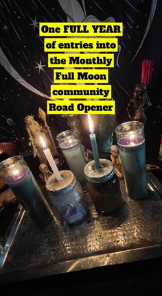 candles are sitting on top of a metal tray with words above them that read, one full year of entries into the mostly full moon community money jar