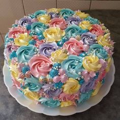 a colorful cake is sitting on a white plate and has flowers all over the top