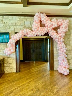 a large arch made out of balloons in the middle of a room with wooden floors