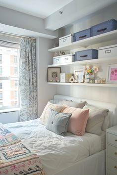 a white bed sitting next to a window in a room with lots of shelves on the wall