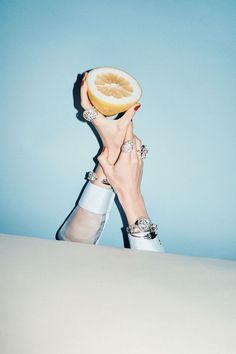 a person holding a slice of fruit up to their face in front of a blue background