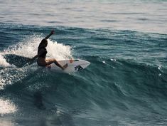 a man riding a wave on top of a white surfboard in the middle of the ocean