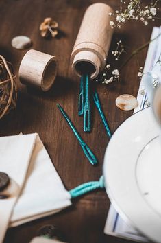 a wooden table topped with lots of different types of crafting supplies next to a cup of coffee