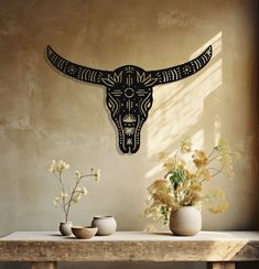 two vases on a table with flowers in front of a bull's head