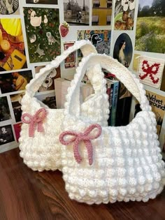 a crocheted white purse with pink bows on the front and bottom, sitting on a table