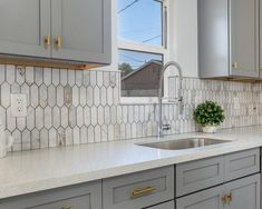 a kitchen with gray cabinets and white counter tops, gold pulls on the faucet