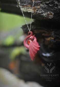 a red dragon necklace hanging from a tree branch