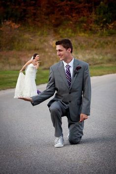 a man kneeling down holding a woman's leg in the middle of the road