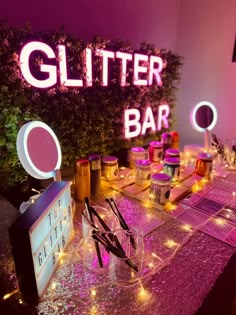 the glitter bar sign is lit up with pink lights and other items on the table