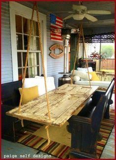 a porch swing made out of an old wooden table and some pillows on the floor