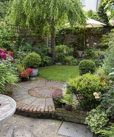 a garden with lots of flowers and plants around it, including an umbrella in the middle