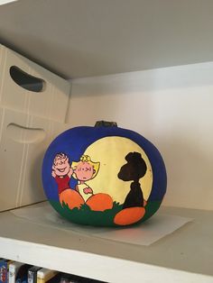 a painted pumpkin sitting on top of a shelf in a room next to a bookcase