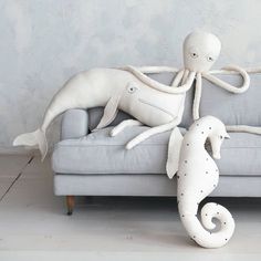 two stuffed animals sitting on top of a couch in front of a sea horse statue