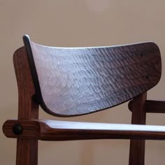 a close up of a wooden chair with a metal seat pad on it's back