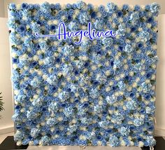 an arrangement of blue and white flowers is displayed in front of a wall with the word, angelinea on it