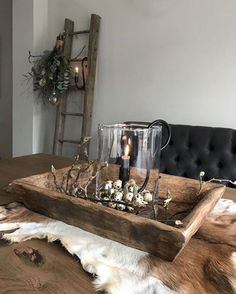 a wooden tray with candles and flowers in it on top of a cowhide rug