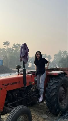 a woman standing next to a red tractor