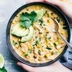 a person holding a bowl of food with avocado and cilantro on the side