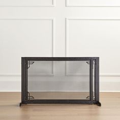 a fireplace screen sitting on top of a hard wood floor next to a white wall