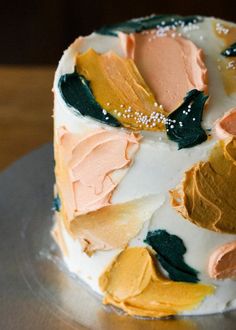 a multicolored cake sitting on top of a silver plate covered in frosting