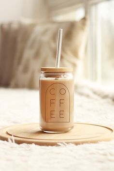 a glass jar with a straw in it sitting on top of a bed