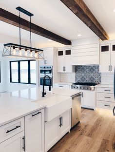 a large kitchen with white cabinets and wood beams on the ceiling is pictured in this image