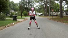 a skateboarder in pink and black is skating down the street with his helmet on