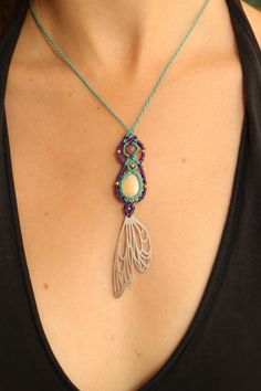 a woman wearing a necklace with a bead and glass pendant hanging from it's side