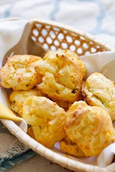 a basket filled with cornbread muffins on top of a cloth covered table