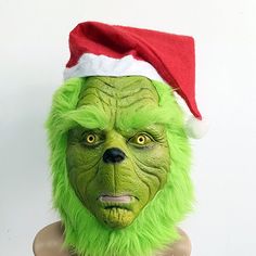 a green man wearing a santa hat and furry fur on top of a mannequin's head