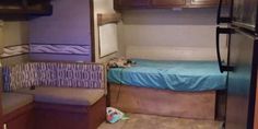 the interior of a camper with a bed, couch and refrigerator freezer in it