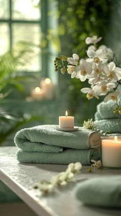 towels and candles on a table with flowers in the background