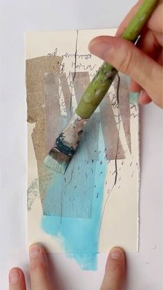 someone is using a brush to paint the bottom of a piece of paper with blue and green acrylic