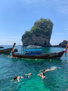 two people swimming in the ocean next to a boat with an island in the background