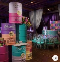 colorful barrels are stacked on top of each other at a wedding or event venue with tables and chairs in the background