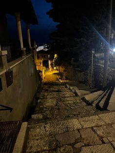 an alley way at night with lights on and stone steps leading up to the building