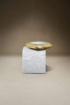 a white and gold object sitting on top of a marble block