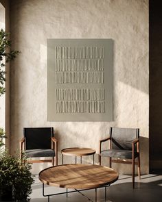 two chairs and a table in front of a wall with an art work on it