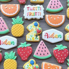 some decorated cookies are on a table with fruit in the shape of letters and numbers