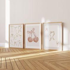 three framed pictures on the wall in an empty room with wood flooring and white walls