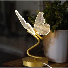 a white butterfly lamp sitting on top of a table next to a potted plant