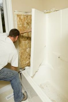 a man working on a shower wall in a bathroom with no tub or bathtub