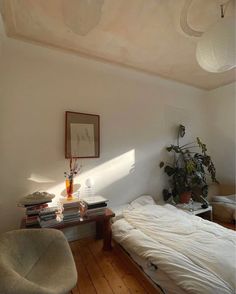 a bedroom with a bed, desk and chair in it next to a potted plant