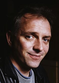 a close up of a person wearing a leather jacket and smiling at the camera with an intense look on his face