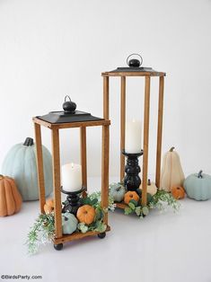 two wooden lanterns with candles and pumpkins on the table next to eachother