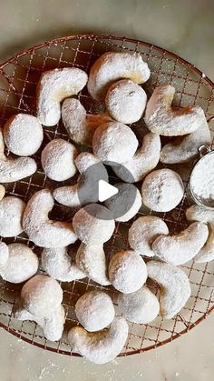 powdered doughnuts are on a wire rack with a scoop of sugar in the middle